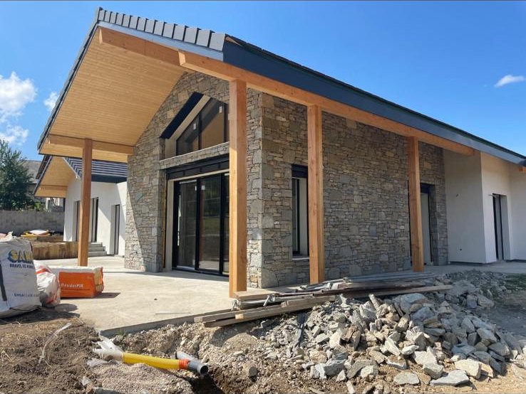 Étape 2 - Second oeuvre : charpente posée, façade en pierres apparentes et poteaux bois, Savoie