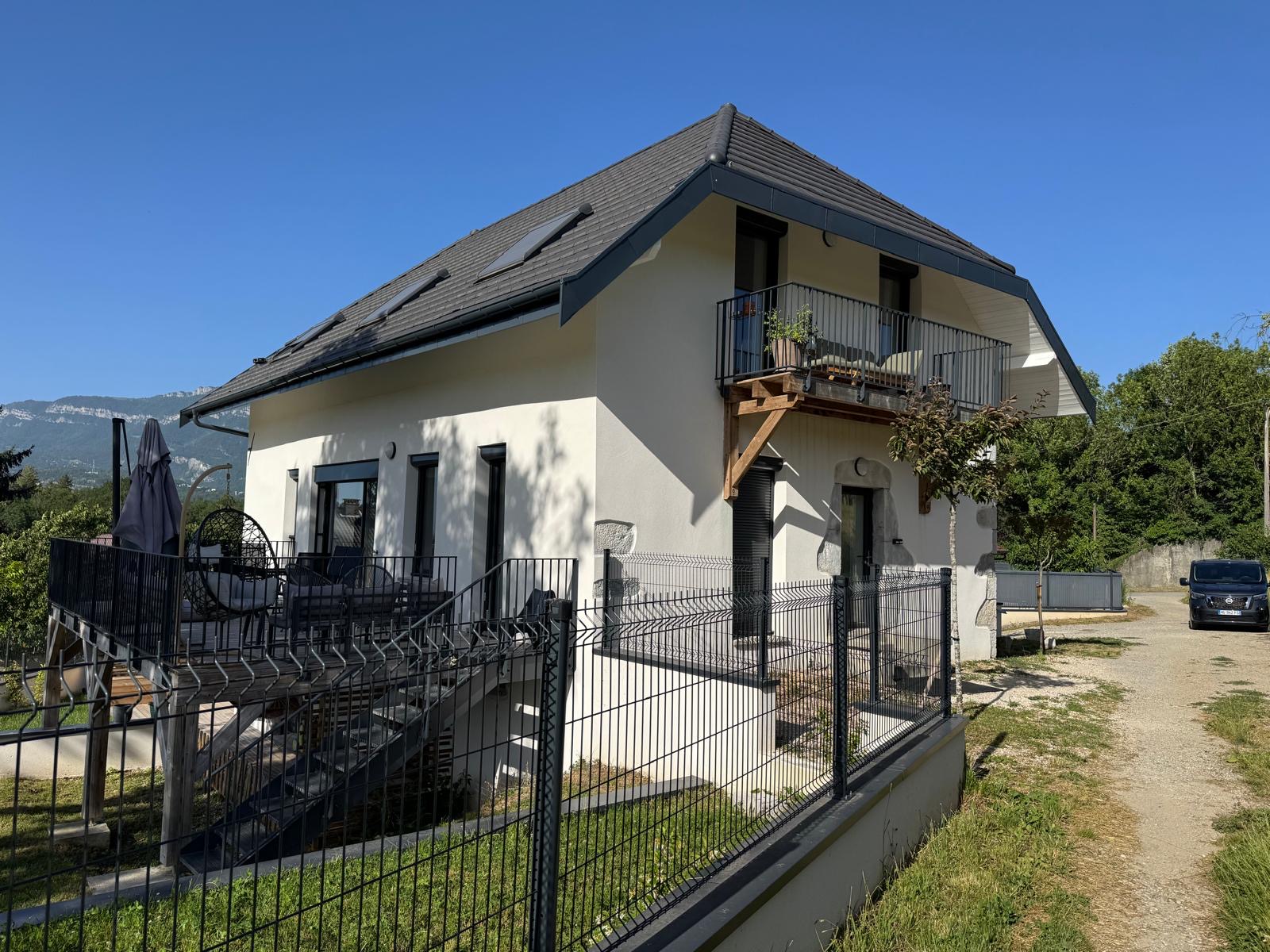 La même maison après rénovation complète par AD'M Construction : façade enduite, balcon et encadrements en pierre