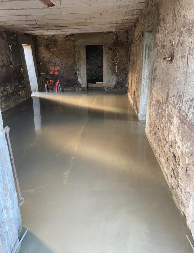Coulage d'une dalle béton à l'intérieur d'une bâtisse en pierre rénovée