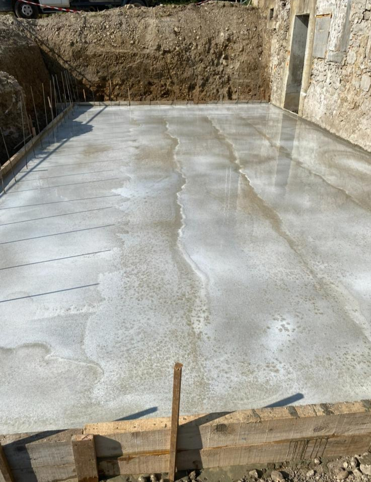 Dalle béton coulée après fouille et préparation du terrain, chantier en Savoie
