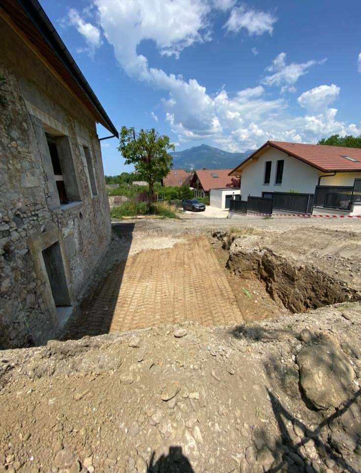 Avant : préparation et nivellement du terrain le long d'une bâtisse en pierre, Savoie